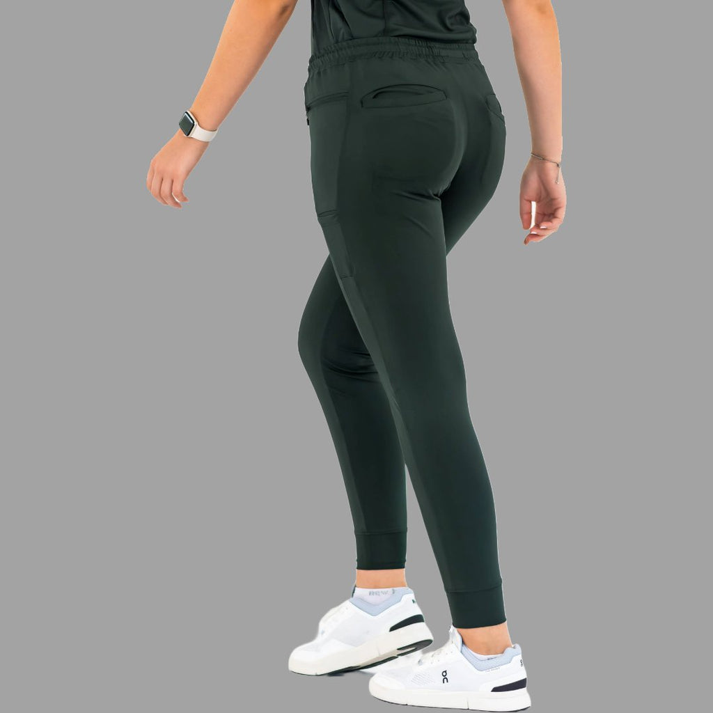 Back three-quarter view of women's scrub joggers 920 super stretch bottle green in a dynamic pose.