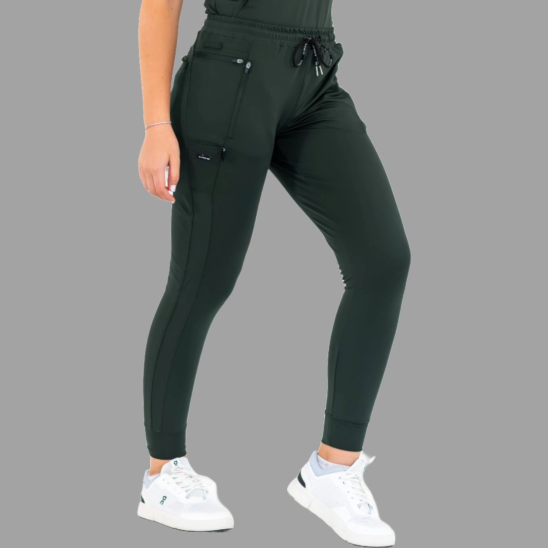 Three-quarter front view of women's scrub joggers 920 super stretch bottle green with legs apart.