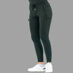 Side view of women's scrub joggers 920 super stretch bottle green with hands in pockets.