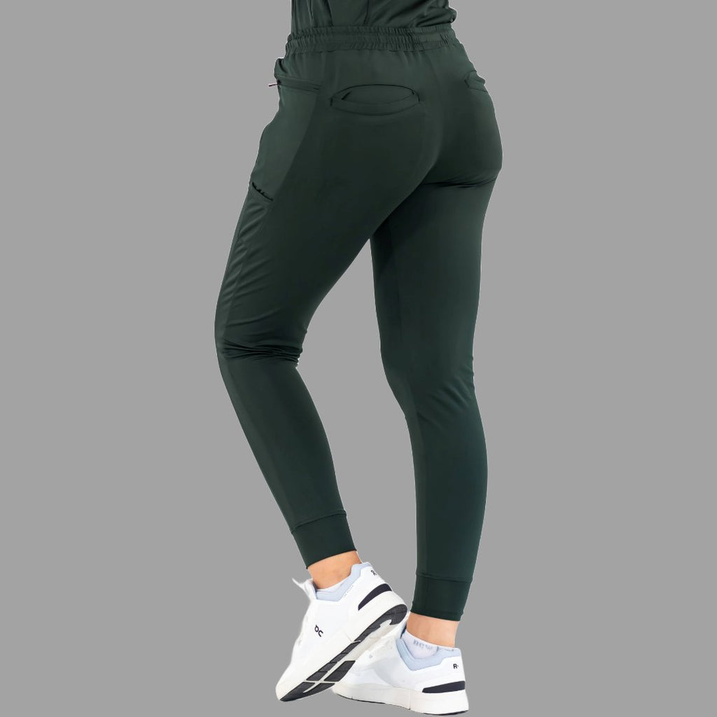 Side back view of women's scrub joggers 920 super stretch bottle green with one foot forward.