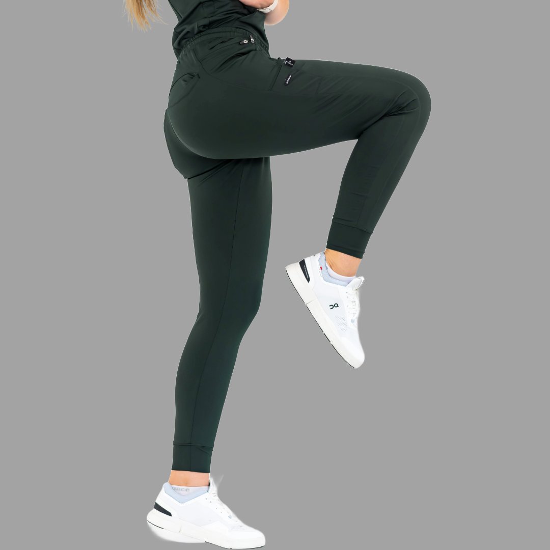 Side view of women's scrub joggers 920 super stretch bottle green with one leg raised.