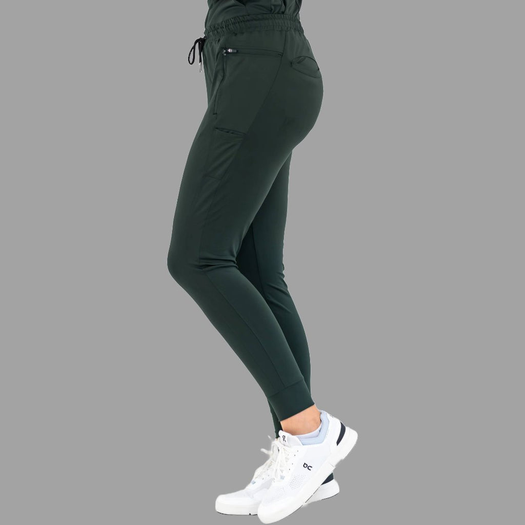 Three-quarter back view of women's scrub joggers 920 super stretch bottle green in a relaxed stance.