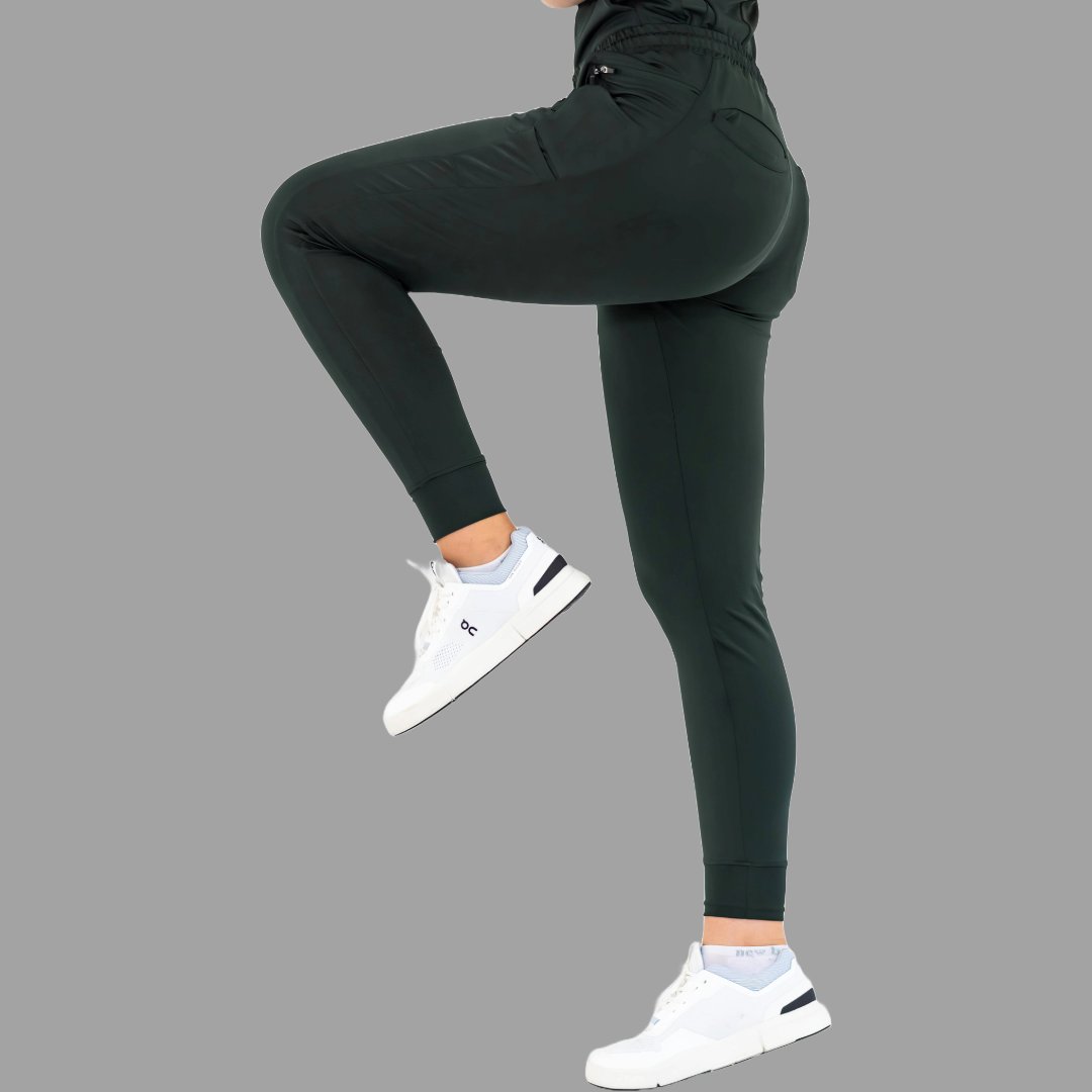 Back side view of women's scrub joggers 920 super stretch bottle green with one leg lifted.
