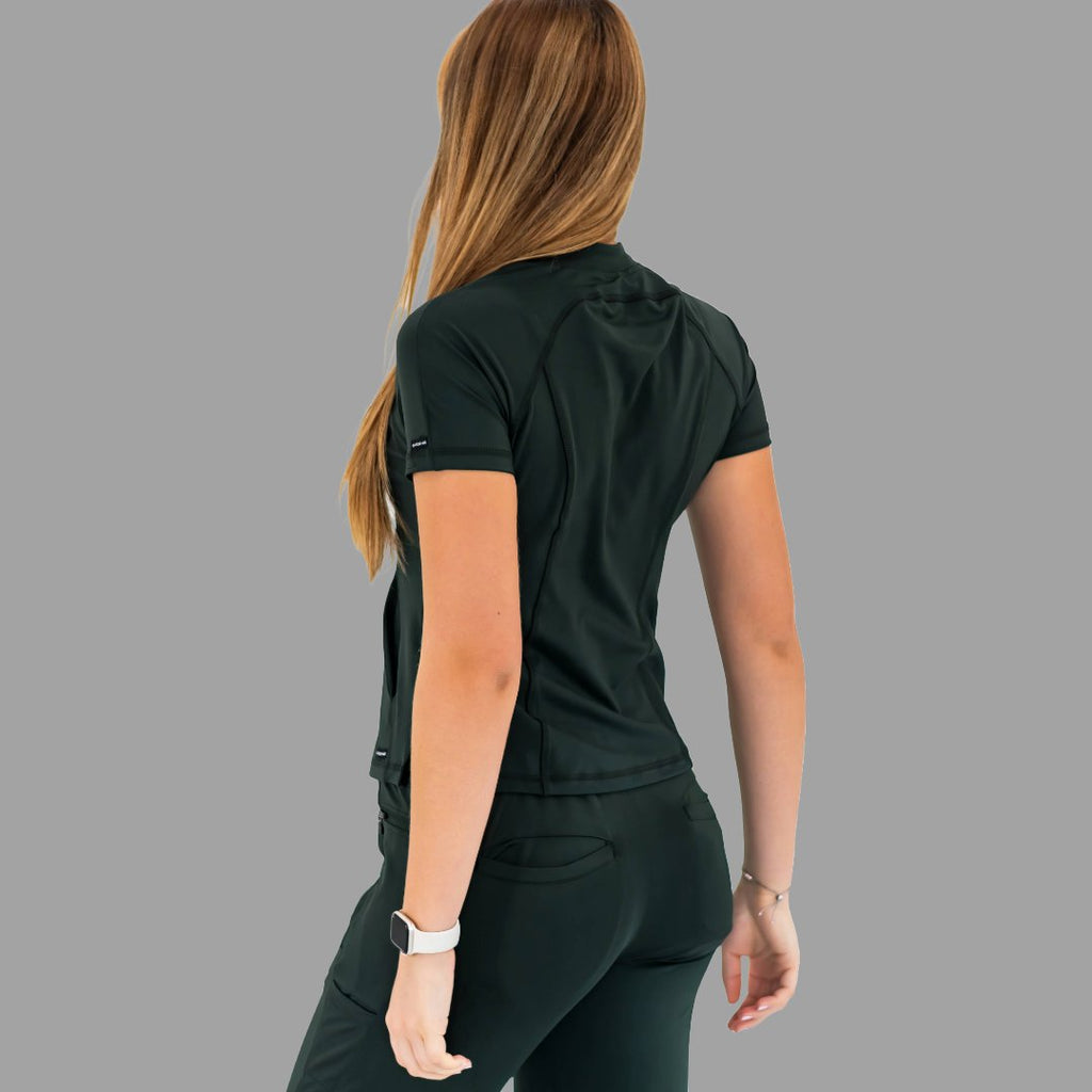 Back view of a woman wearing a bottle green 920 super stretch scrub top, looking over shoulder.