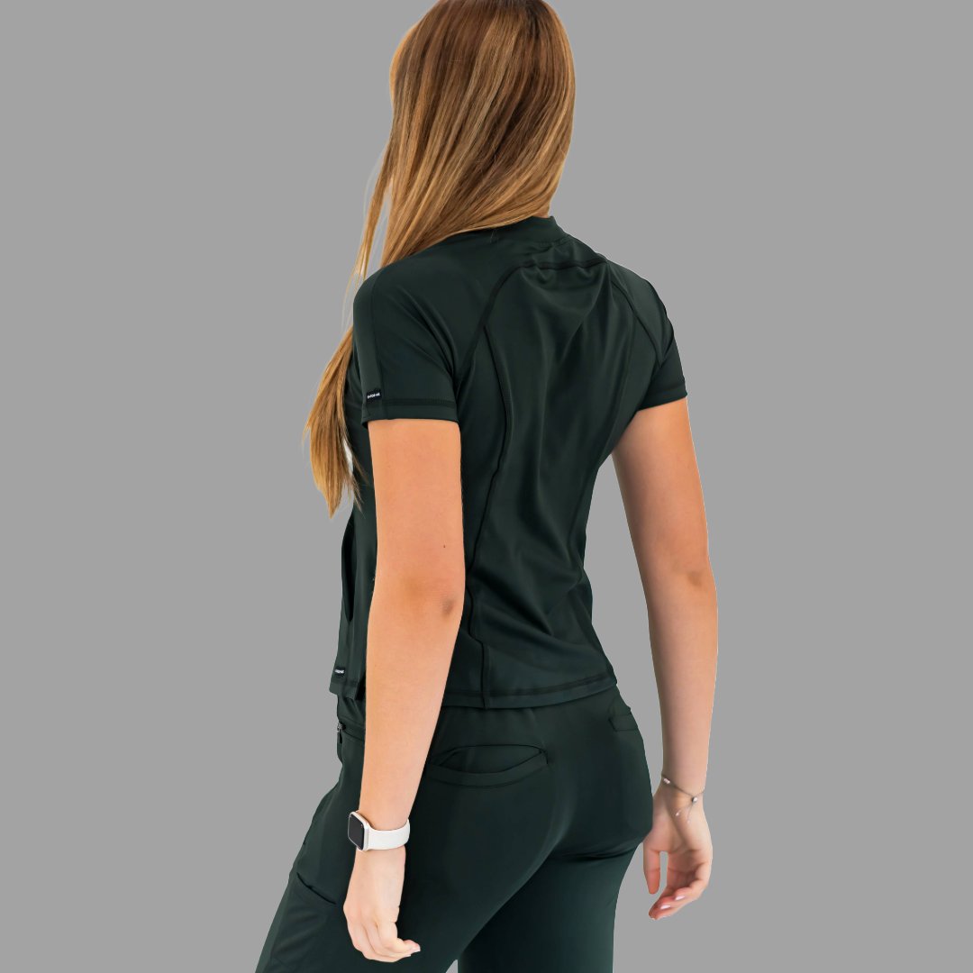 Back view of a woman wearing a bottle green 920 super stretch scrub top, looking over shoulder.
