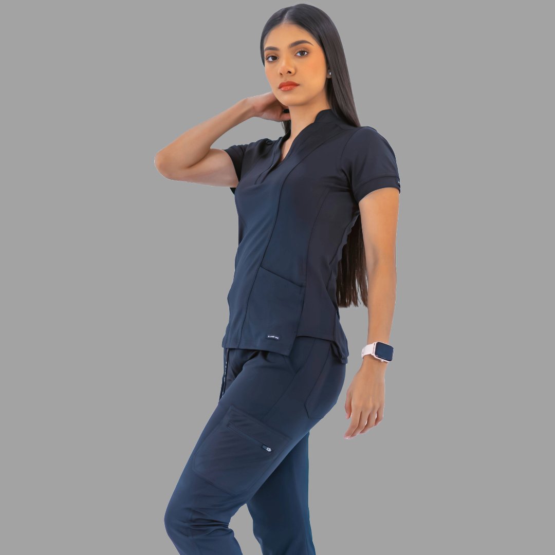 Full body view of a woman wearing a navy blue Style 930 scrub top and matching pants, posing against a grey background.