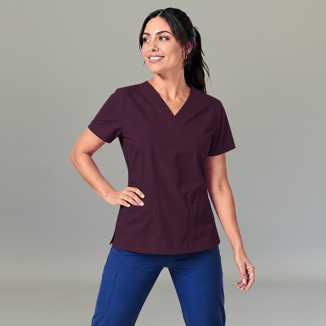 Mujer modelando filipina quirúrgica 502 color vino cherry, vista frontal combinada con pantalón azul.