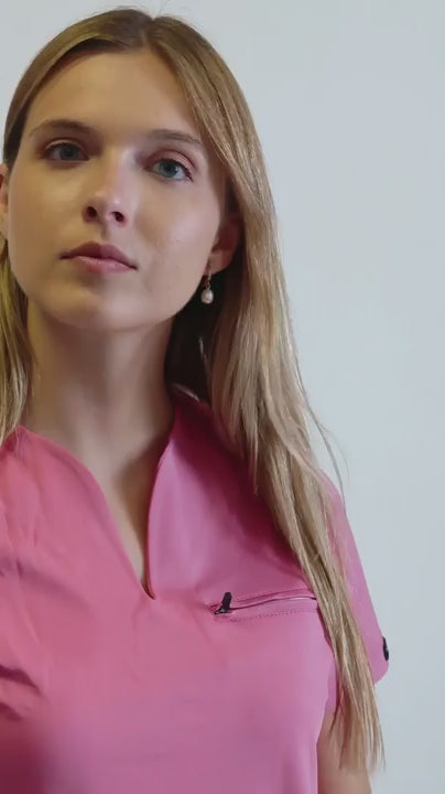 Video del uniforme 915 palo de rosa: filipina de cuello en V, bolsillo superior con cierre y pantalón acampanado coordinado.
